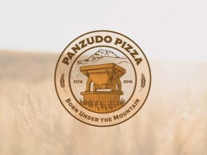 Logo of Panzudo Pizza against a wheat field backdrop